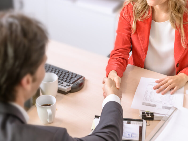 a man and woman shaking hands across a table